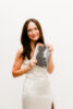 Smiling woman in elegant white dress holding a copy of Pulp Magazine with her on the cover.